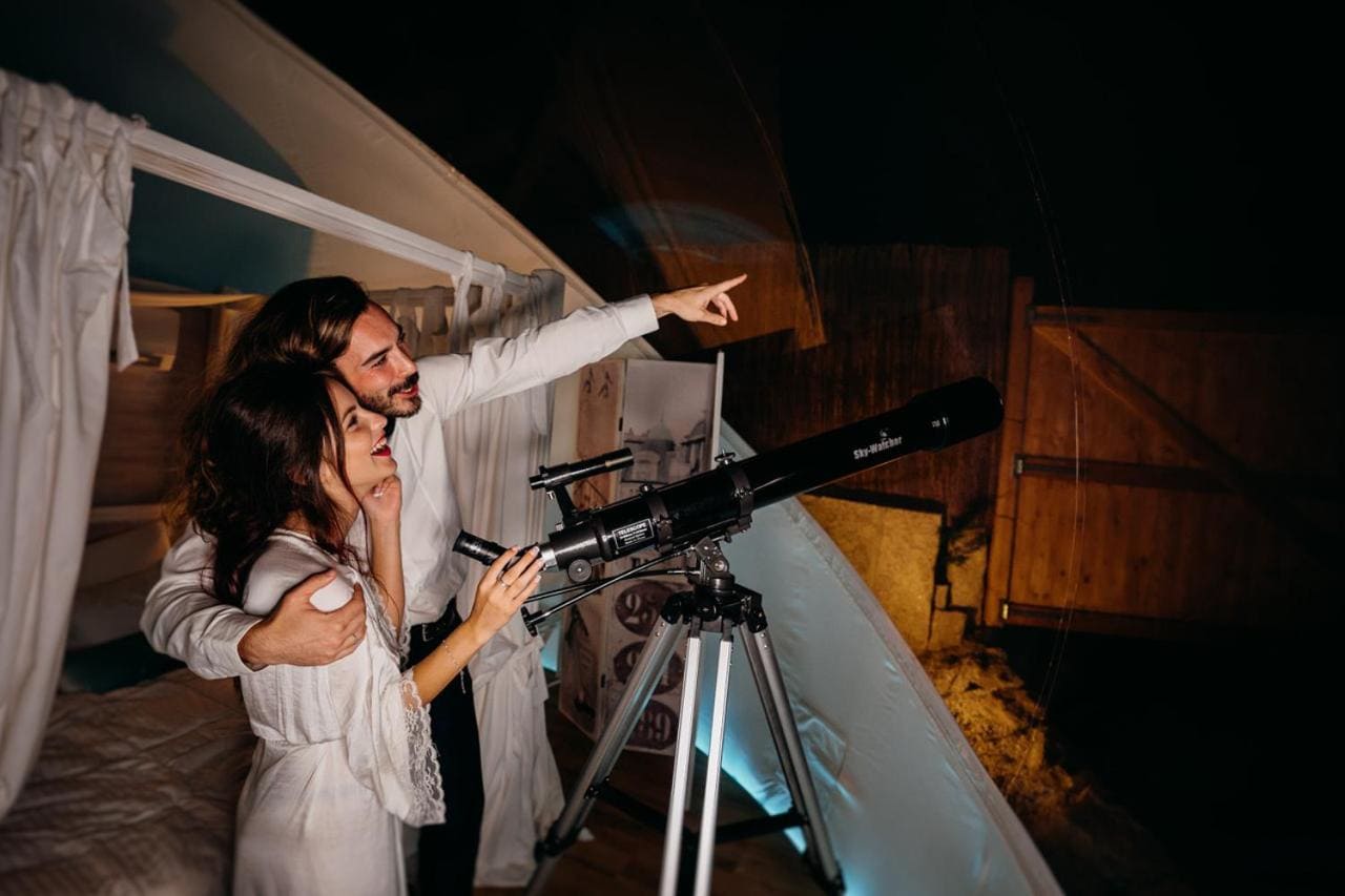 pareja en una noche de estrellas con un cupula inflable en telescopio dentro de la burbuja hinchable con cama en Alojamiento viendo las estrellas con telescopio en Albarari Sanxenxo galicia